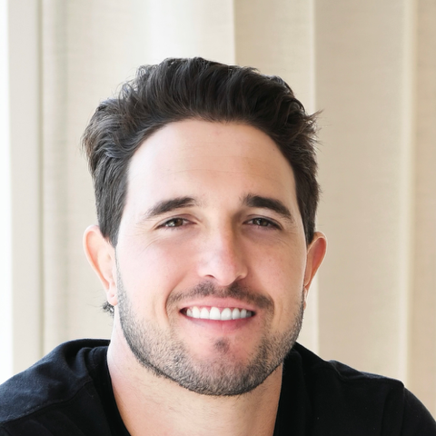 Dr Justin Maia smiling in front of an off white background